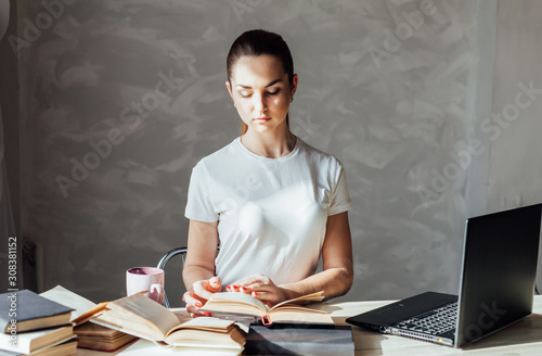 girl is preparing for the exam reading book works at the computer photo