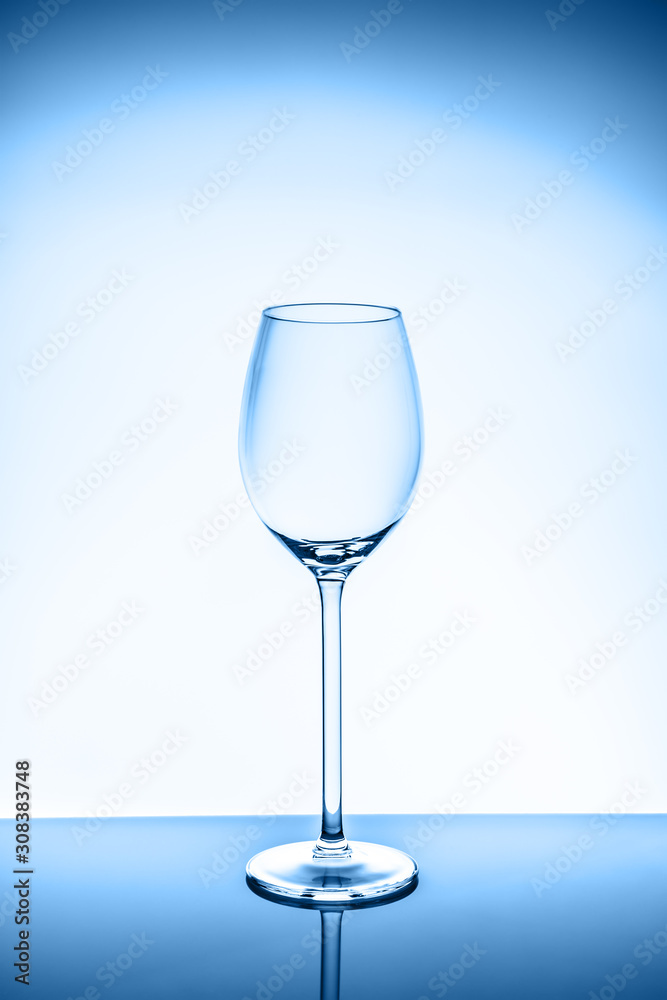 Wineglass on the light background. Fine cristal glassware concept. Vertical, toned in blue Wineglass on the light background. Fine cristal glassware concept. Vertical, toned in blue