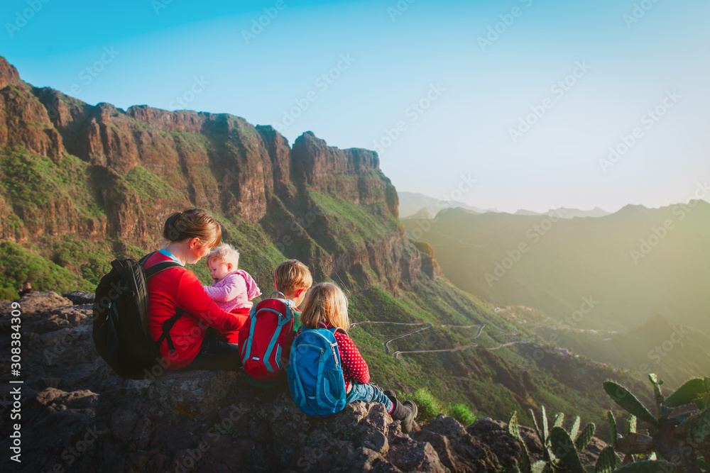 mother with three kids hiking in mountains, family travel in nature