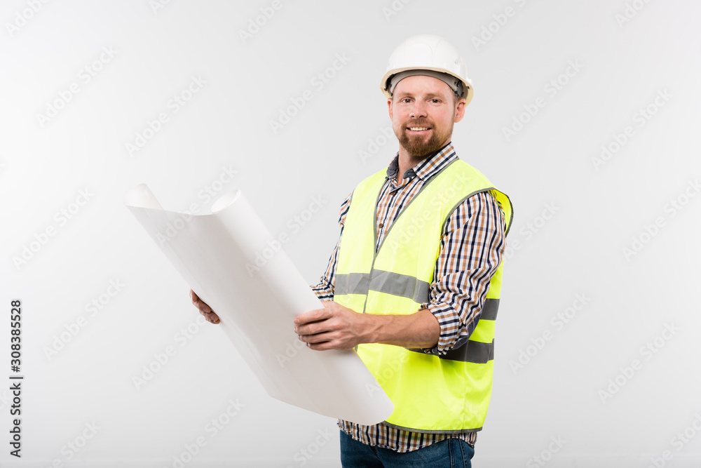 Successful young foreman in helmet and workwear holding paper with sketch Successful young foreman in helmet and workwear holding paper with sketch