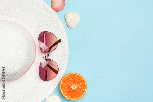 White hat, glasses, shells, orange on a blue background. Greeting card. The concept of vacation sea summer travel. Copy space