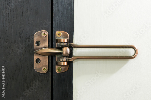 Safety latch guard on hotel room door, on black door and white wall,  Locked doors in hotel.