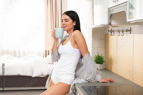 Obraz na plátne Beautiful young woman in white underwear drinking coffee at home