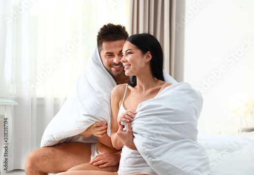 Young couple in underwear under blanket at home