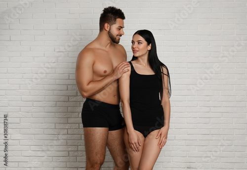 Young couple in black underwear near white brick wall