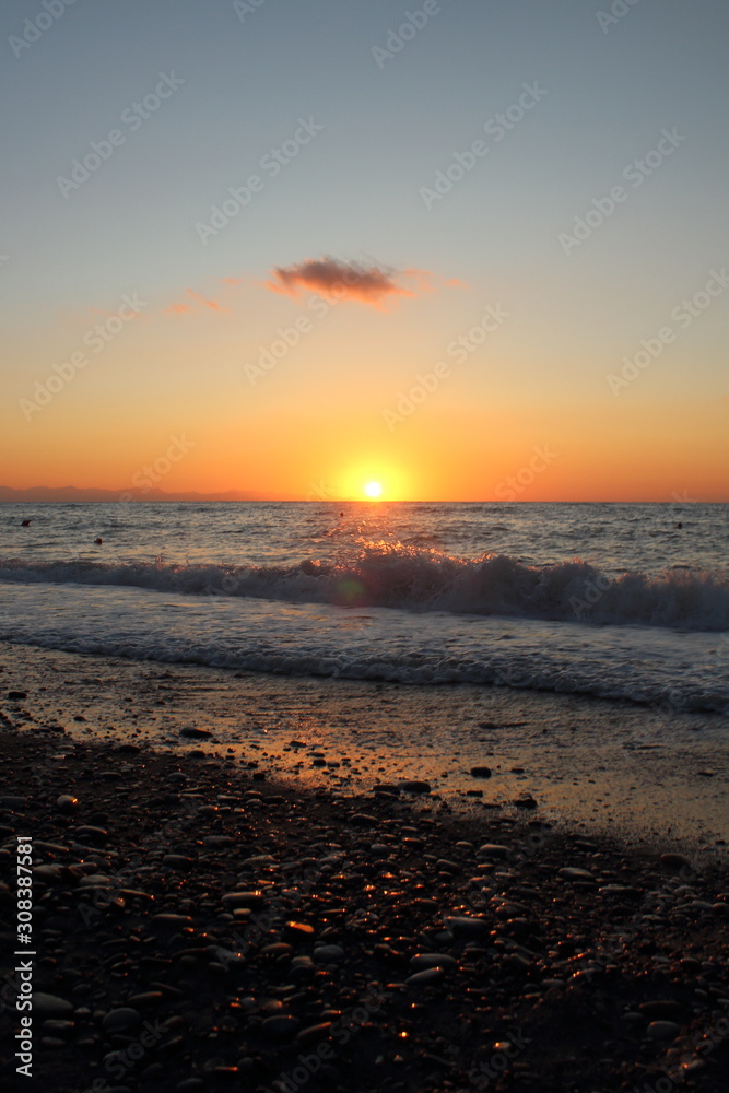 Fototapeta premium the sun setting behind the promontory with the sea in the foreground