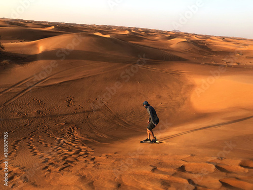 Man sandboarding in uae desert