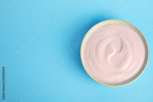 Tasty organic yogurt on light blue background, top view. Space for text