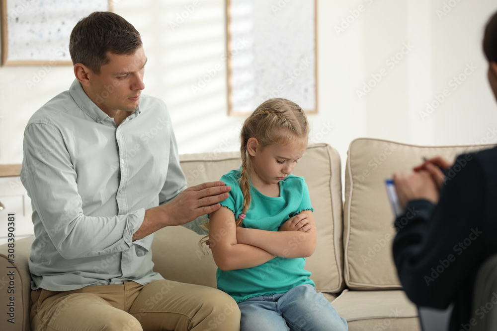 Little girl and her father on appointment with child psychotherapist indoors Little girl and her father on appointment with child psychotherapist indoors
