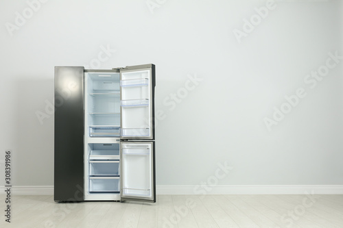 Modern refrigerator near light grey wall. space for text
