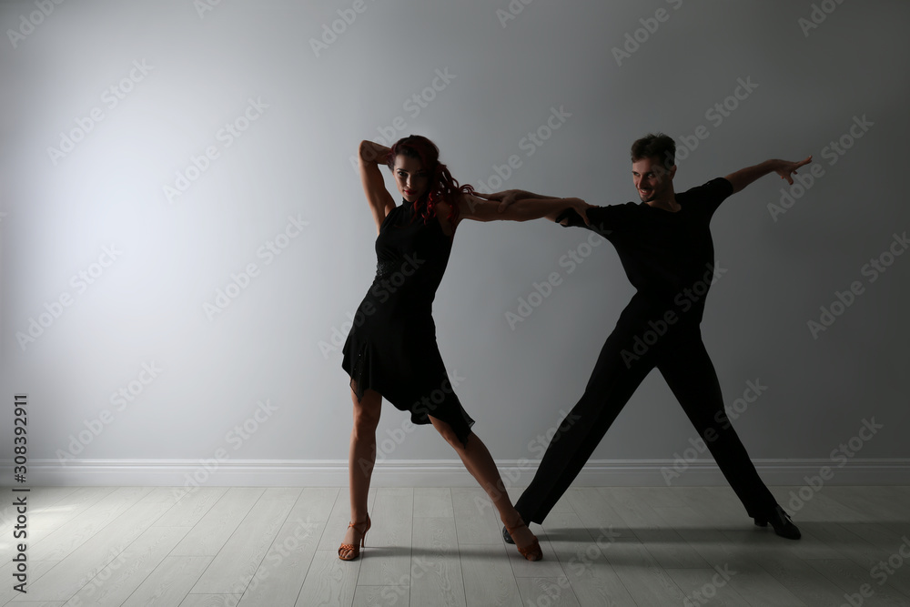 Fototapeta Beautiful young couple dancing near light wall