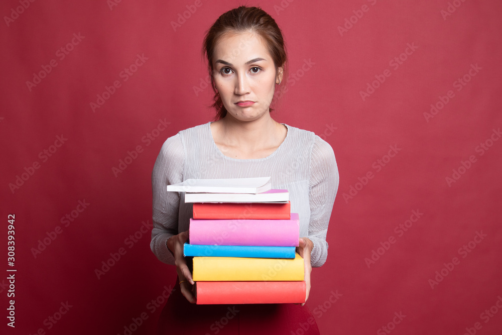 Unhappy young Asian woman studying with may books. Unhappy young Asian woman studying with may books.