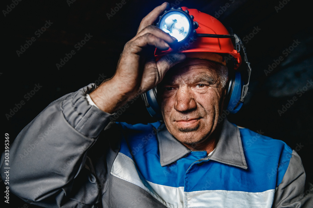 Portrait miner coal man in helmet with lantern in underground mine. Concept industrial engineer Portrait miner coal man in helmet with lantern in underground mine. Concept industrial engineer