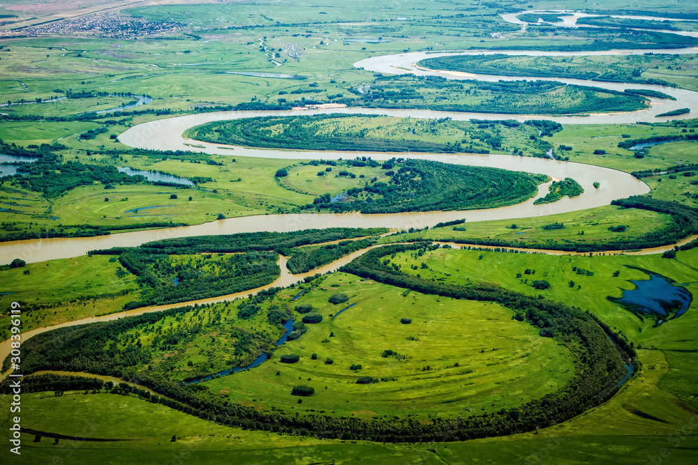 View of the valley of a meandering river among green fields and forests. Aerial photography