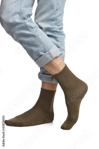 Cropped shot of a man's cross legs in blue jeans, staying on a white background. It is khaki socks on his foots. 