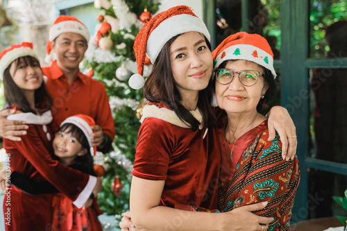 asian daughter and senior mother hug embracing on christmas eve
