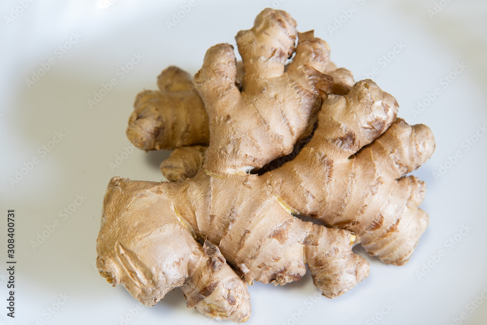 Ginger root on plate. Fresh organic ginger root on white plate. No people, isolated. Fresh healthy spice, natural medicine.
