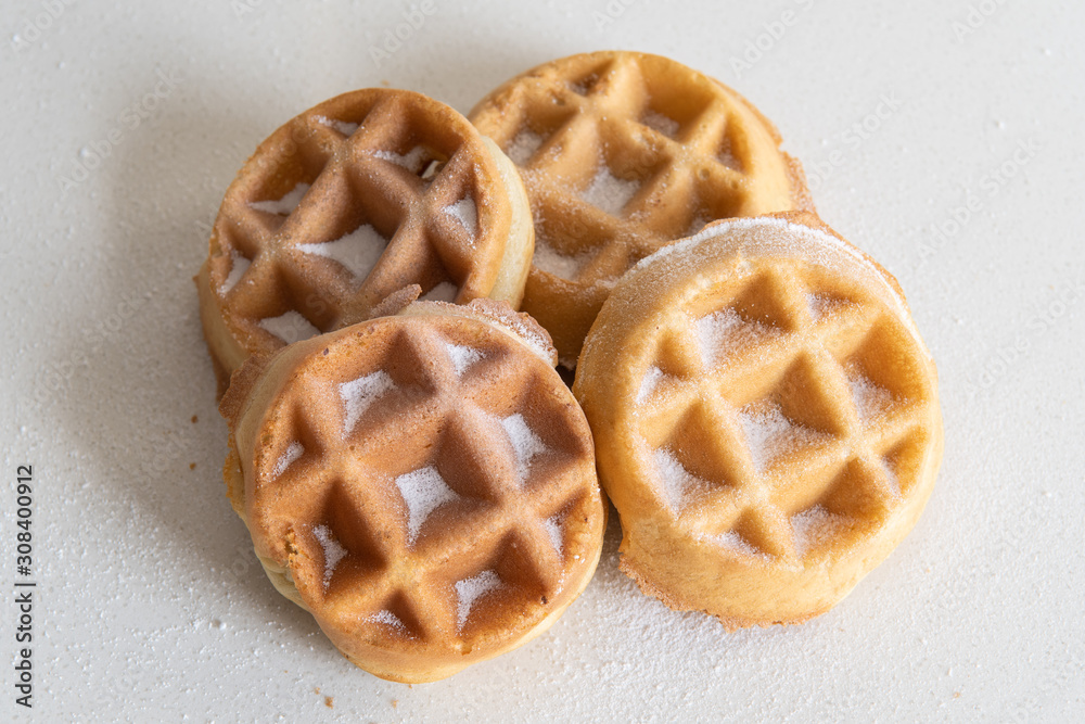 4 pieces of golden brown waffles covered with powder sugar isolated on white background. Morning breakfast baked food. 4 pieces of golden brown waffles covered with powder sugar isolated on white background. Morning breakfast baked food.