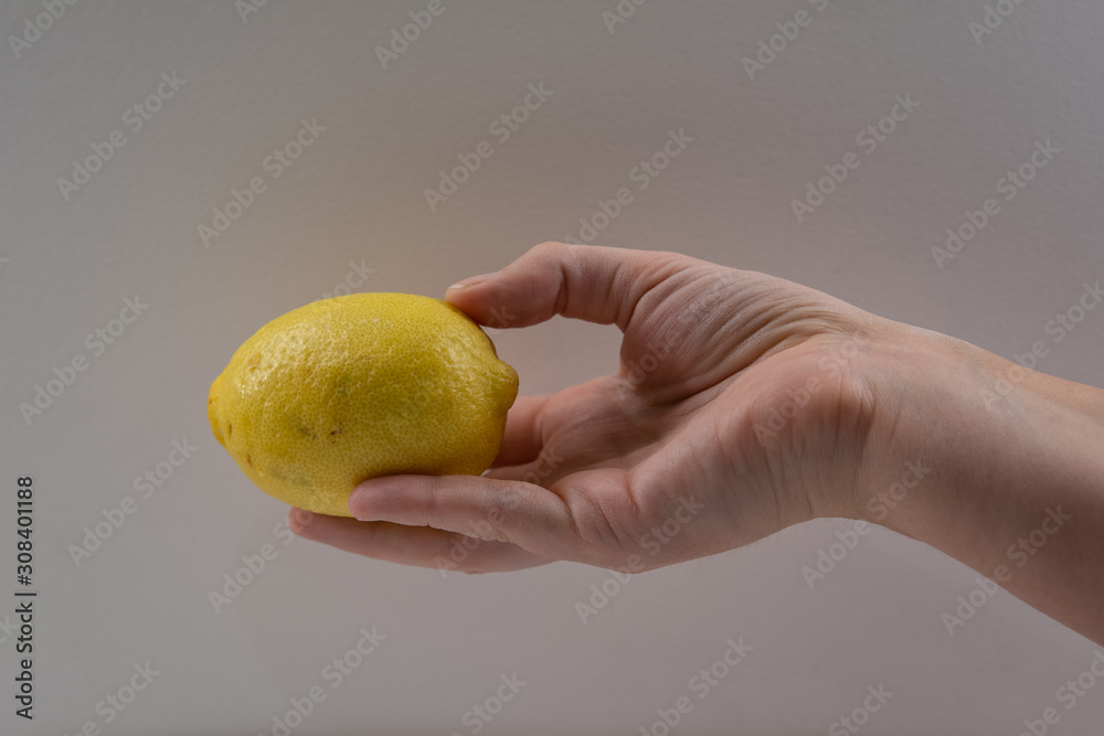 Hand of middle aged woman holding fresh organic lemon. White background. Fresh citrus fruit. Hand of middle aged woman holding fresh organic lemon. White background. Fresh citrus fruit.