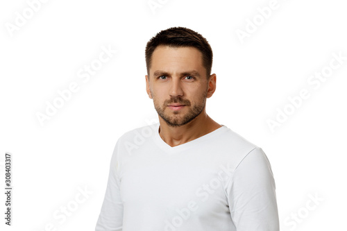 man gazes steadily. Close-up portrait of handsome bearded man in white shirt looking at camera isolated on white background
