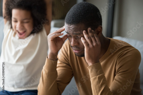 Tired black dad suffer from headache and disobedient daughter