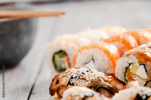 Sushi and soy sauce in a bowl and wooden chopsticks on a gray wooden table. Japanese food. Sushi Set. Variety of rolls. Menu.