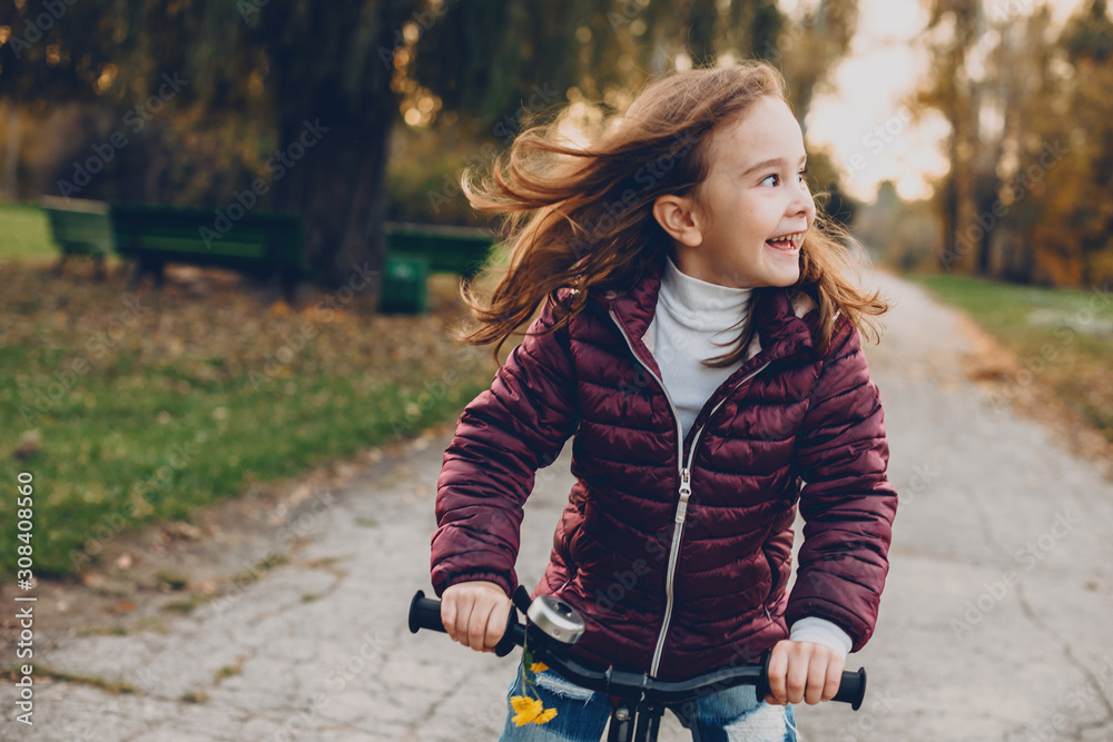 Portrait of a beautiful girl riding a bicycle and looking away laughing against sunset in the park. Portrait of a beautiful girl riding a bicycle and looking away laughing against sunset in the park.