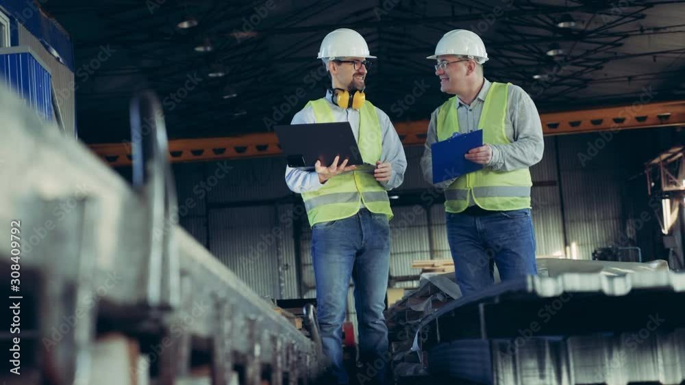 Professional heavy Industry Engineers. Male workers are talking in a plant unit with building supplies Professional heavy Industry Engineers. Male workers are talking in a plant unit with building supplies