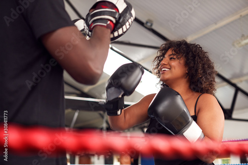 Male Personal Trainer Sparring With Female Boxer In Gym Using Training Gloves photo
