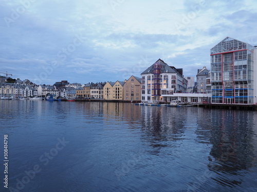 Yacht port and secessionist buildings reflected in water in european city of Alesund at Romsdal in Norway at evening