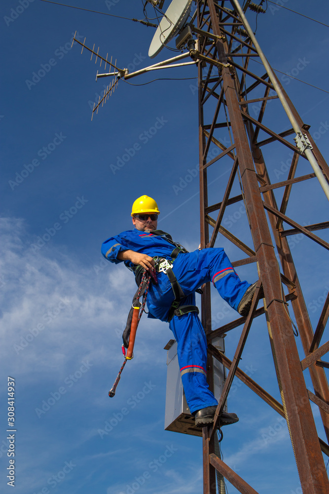 Technician with safety belt working on electric power pole Technician with safety belt working on electric power pole