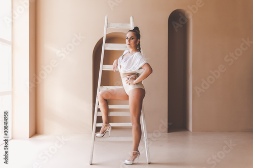 Obraz na płótnie Beautiful woman dancer in sexy lingerie posing with ladder in studio