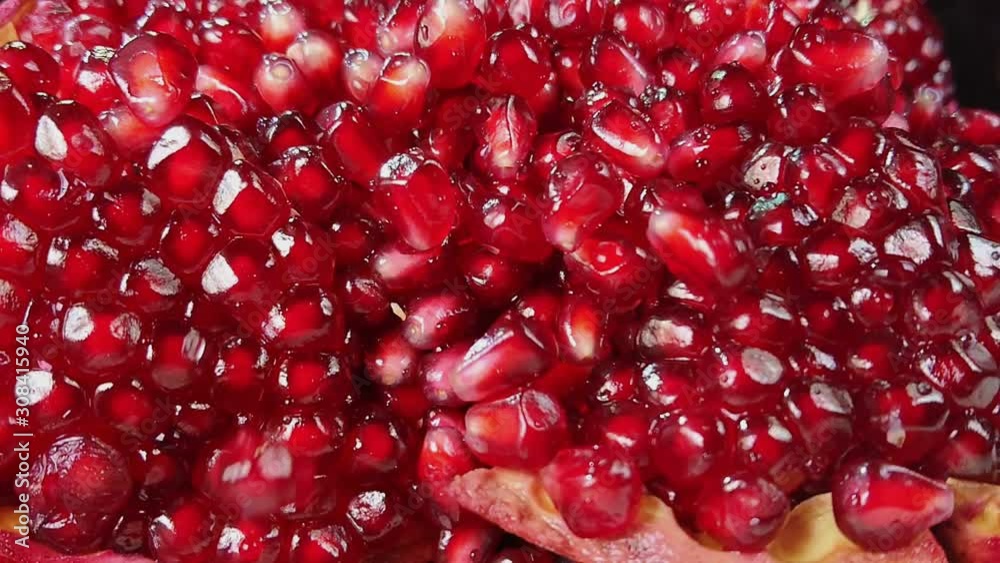 Shining juicy grains of red pomegranate bouncing on other grains Shining juicy grains of red pomegranate bouncing on other grains