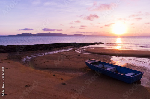 Small boat on an empty beach at sunset