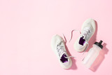 White sneakers and a bottle of water under morning sunlight on a pink background. Concept, jogging, running, fitness, cross fit. Morning run. Banner. Flat lay, top view