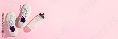 Obraz na plátně White sneakers and a bottle of water under morning sunlight on a pink background