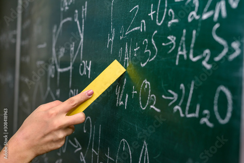 Female hand pointing at chemical formula on blackboard close up