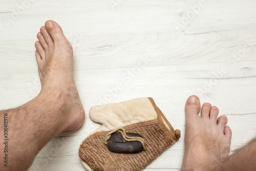 Man's bare feet on and tar soap with and a washcloth on wooden board