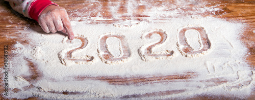 Obraz na płótnie Inscription 2020 with a children's hand on a flour board (New Year background - concept) w salonie