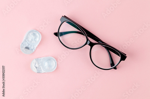 Glasses and contact lenses on pink background. Concept of vision correction. Top view, copy space.
