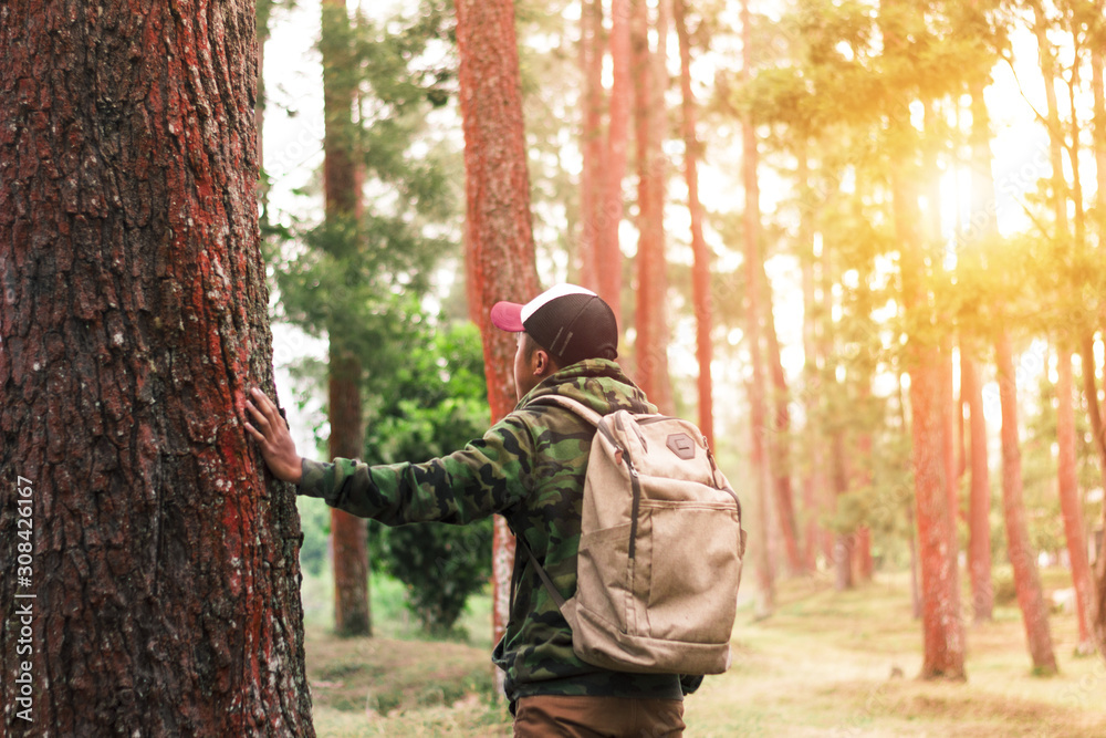 Traveler man with backpack standing near tropical jungle at sunny day Traveler man with backpack standing near tropical jungle at sunny day