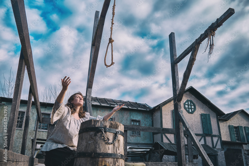 Woman raises her hands to the sky at the place of execution, the area with the gallows at the scaffold