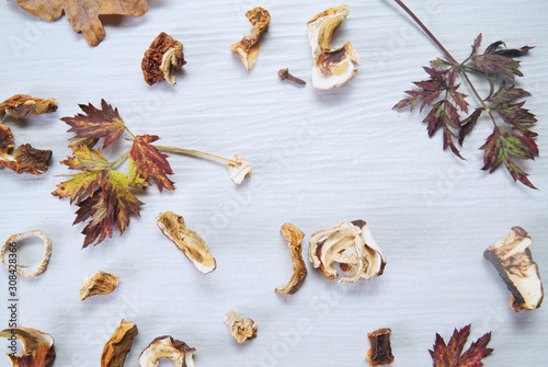 Dried mushrooms and autumn leaves on a background of white wood. 