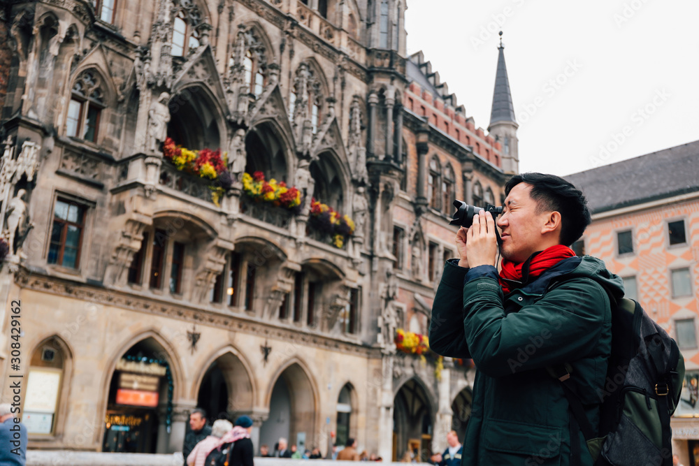© twinsterphoto - Young Asian traveling backpacker in city centre in Europe. Man taking photos in Marienplatz square, Munich, Germany. Traveling to Europe © twinsterphoto - Young Asian traveling backpacker in city centre in Europe. Man taking photos in Marienplatz square, Munich, Germany. Traveling to Europe