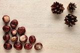Chestnuts and pine cones on wooden background. Flat lay, top view