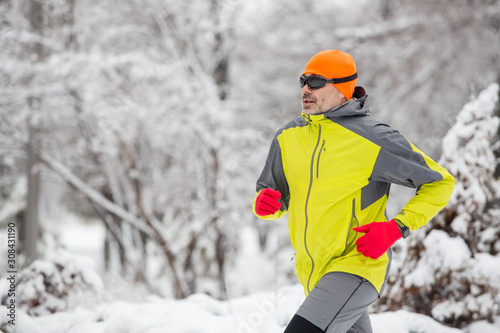 Man running in the forest in winter time. Man wearing sportswear at winter in park 