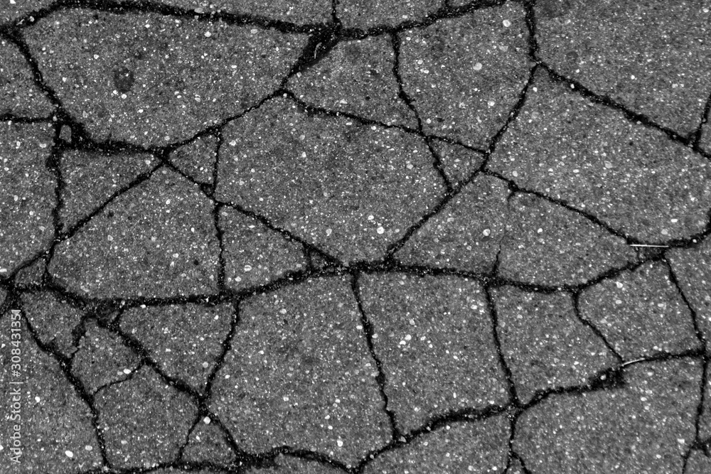 Fototapeta premium Damaged asphalt surface in black and white.