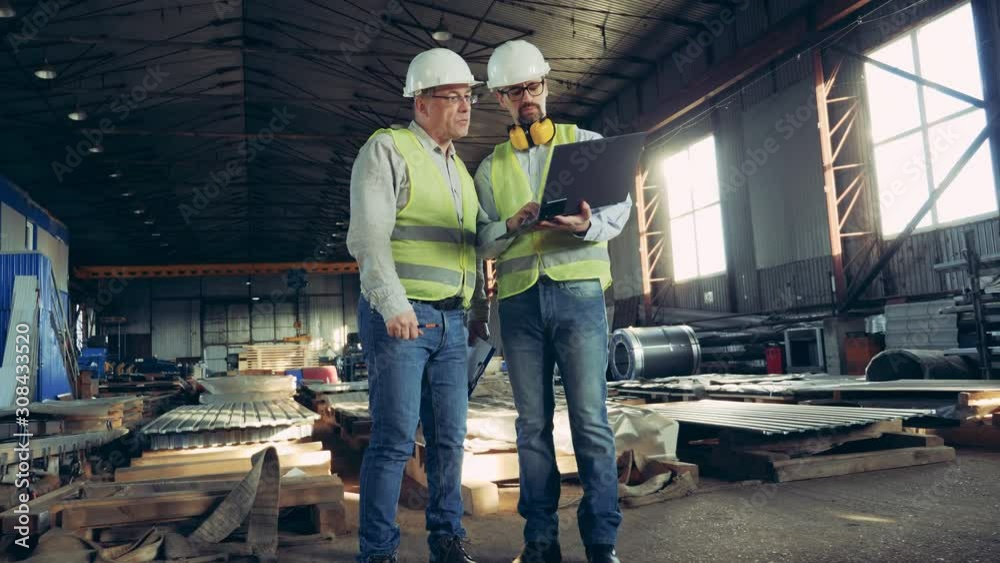 Male employees are talking in a unit with construction materials. Male engineers at industrial factory. Male employees are talking in a unit with construction materials. Male engineers at industrial factory.