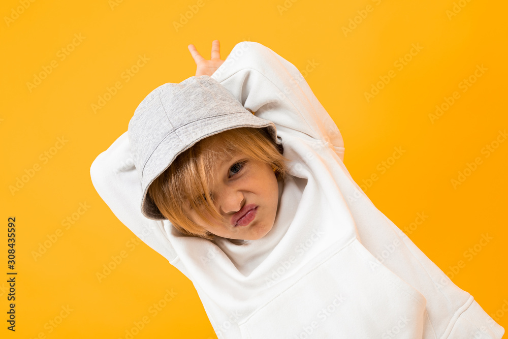 blond boy with panama grimaces on an orange studio background blond boy with panama grimaces on an orange studio background