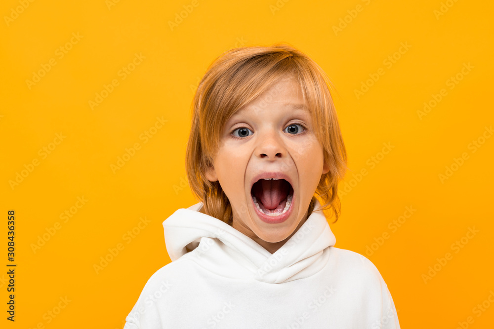 blond boy grimaces on an orange studio background close-up blond boy grimaces on an orange studio background close-up